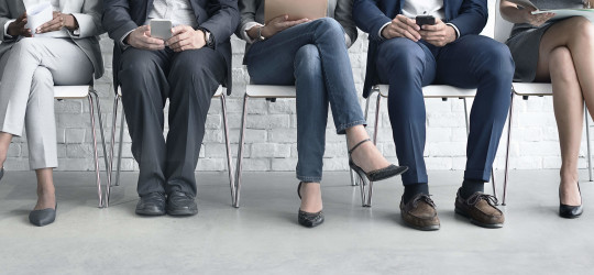Row of job candidates sitting on seats waiting for interview