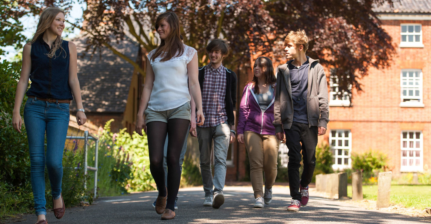 Students walking on pavement through Paston Lawns campus