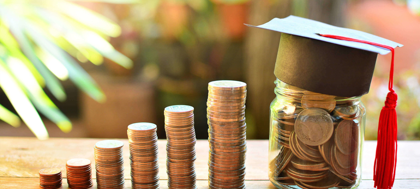 Columns of pennies next to jar of pennies wearing graduation cap