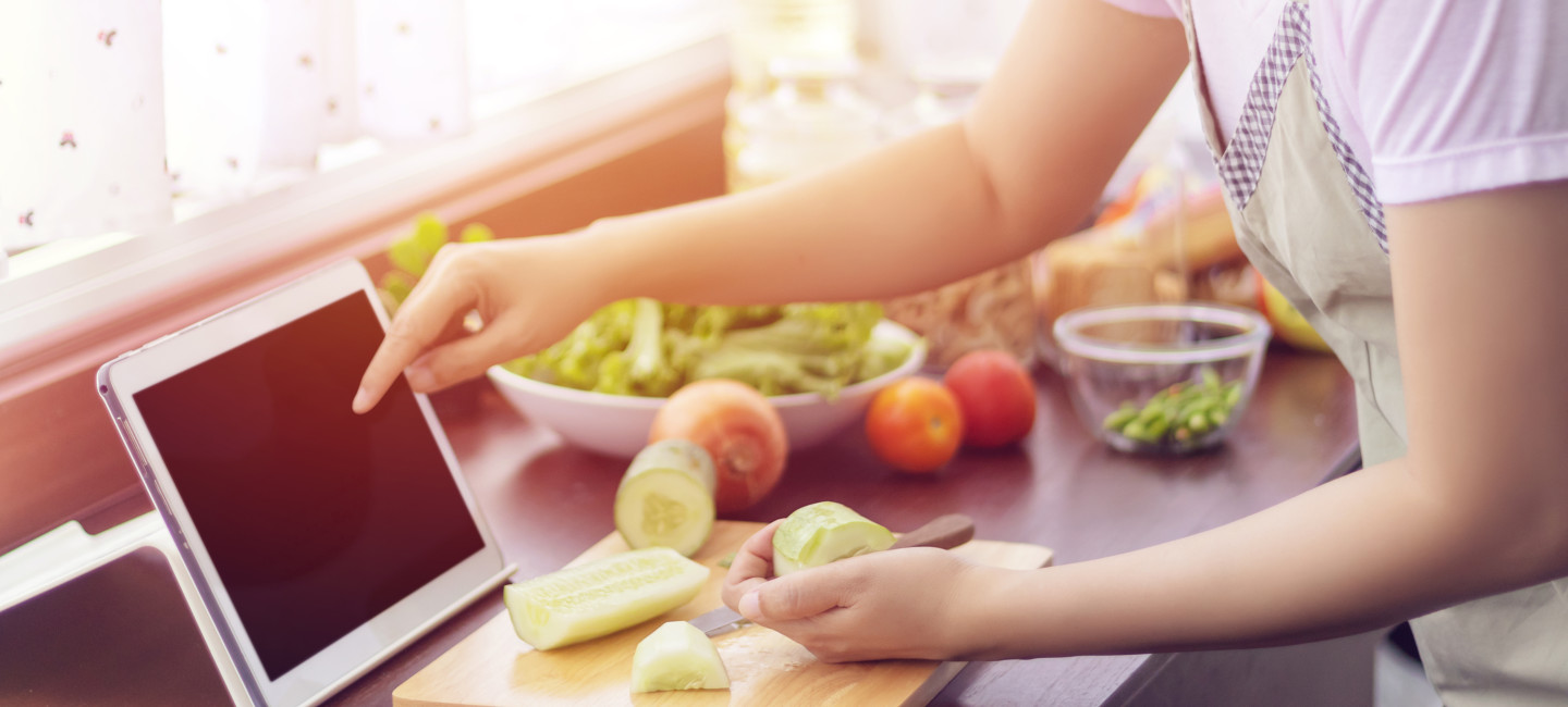 Person cooking at home, scrolling through tablet