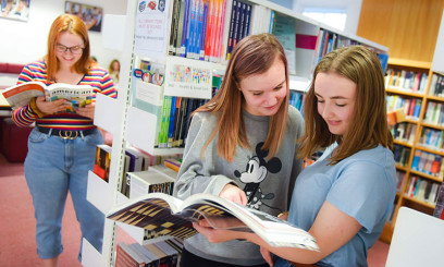 Students reading open text books in Paston College library